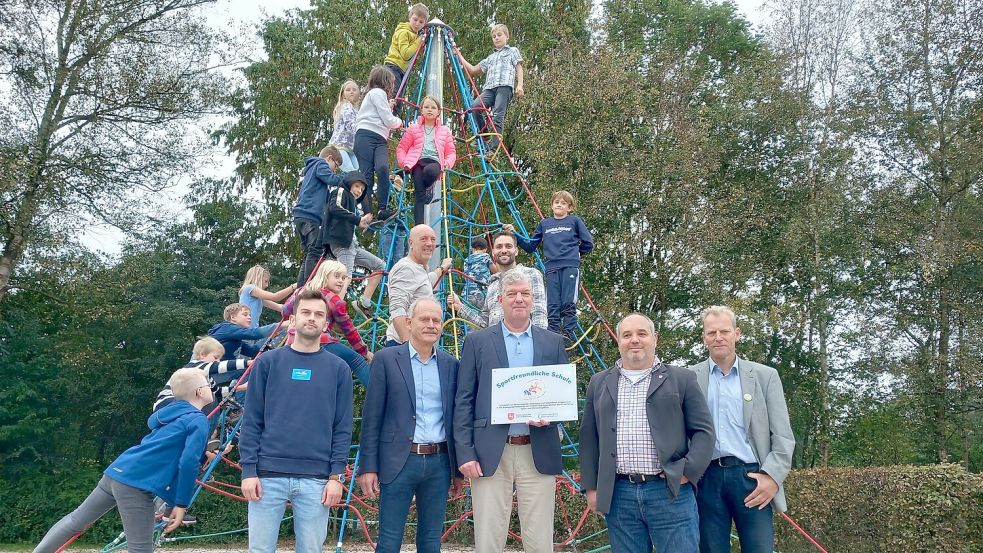 Freude in Langholt über die Auszeichnung als Sportfreundliche Schule bei (vorne, von links) Marcel Degner vom Hauptamt der Gemeinde Rhauderfehn, Jörg Kromminga (Vorsitzender Kreissportbund), Schulleiter Nanno Heddens, Thomas Ernhardt (Fachberater Schulsport der Landesschulbehörde), Rhauderfehns Bürgermeister Geert Müller, sowie (hinten, von links) Gerhold Möhlmann und Philipp Heitz, beide Sportlehrer an der Grundschule Langholt mit Schulkindern. Foto: Scherzer