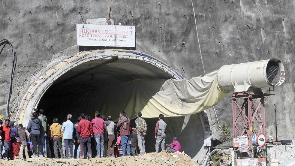 Menschen beobachten Rettungs- und Hilfsmaßnahmen an der Stelle eines im Bau befindlichen Straßentunnels, der im indischen Bundesstaat Uttarakhand eingestürzt ist. Foto: dpa