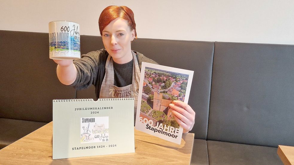 Bei Sandra Huisinga von der Bäckerei Bruns an der Stapelmoorer Hauptstraße kann man den Jubiläumskalender, die Festschrift und die Tasse zum 600-jährigen Jubiläum des Dorfes kaufen. Foto: Gettkowski