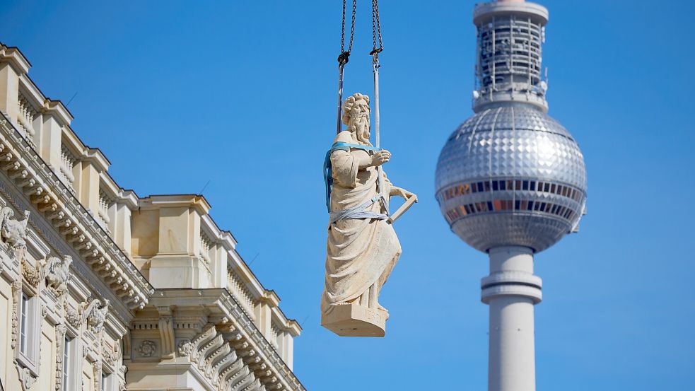 Eine Skulptur des Propheten Jeremias, die für die Kuppel-Balustrade des Humboldt-Forums bestimmt ist, schwebt bei ihrer Montage über dem Forum in Sichtweite des Fernsehturms. Foto: picture-alliance/dpa