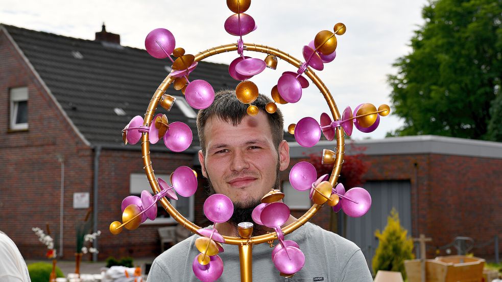 Philipp Sager blickt beim Flohmarkt in Schwerinsdorf durch ein von ihm erstelltes Windspiel. Foto: Stromann