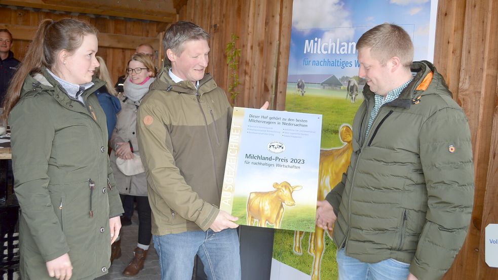 Weert Baack überreicht Marike Loesing (links) und Heiner Cordes (rechts) das nach außen sichtbare Symbol für den Erfolg ihrer täglichen Arbeit.