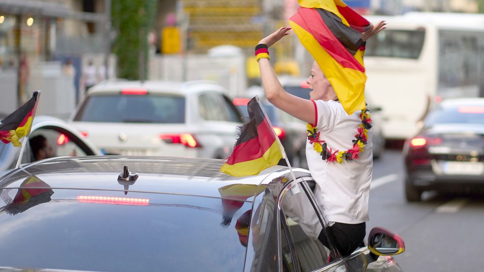 Fan-Jubel auf der Straße ist in Ordnung. Doch wer sich und andere nicht gefährden will, lehnt sich nicht zu weit aus dem Autofenster. Symbolbild: Thomas Frey/dpa