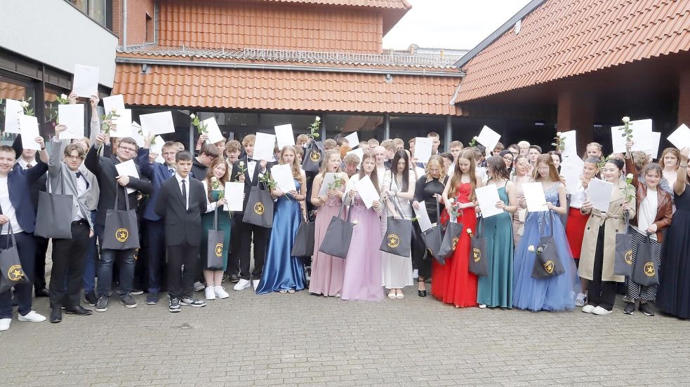 Die Schülerinnen und Schüler des neuen und zehnten Jahrgangs der IGS Barßel halten vor dem Schulgebäude ihre Zeugnisse in den Händen. Foto: Passmann