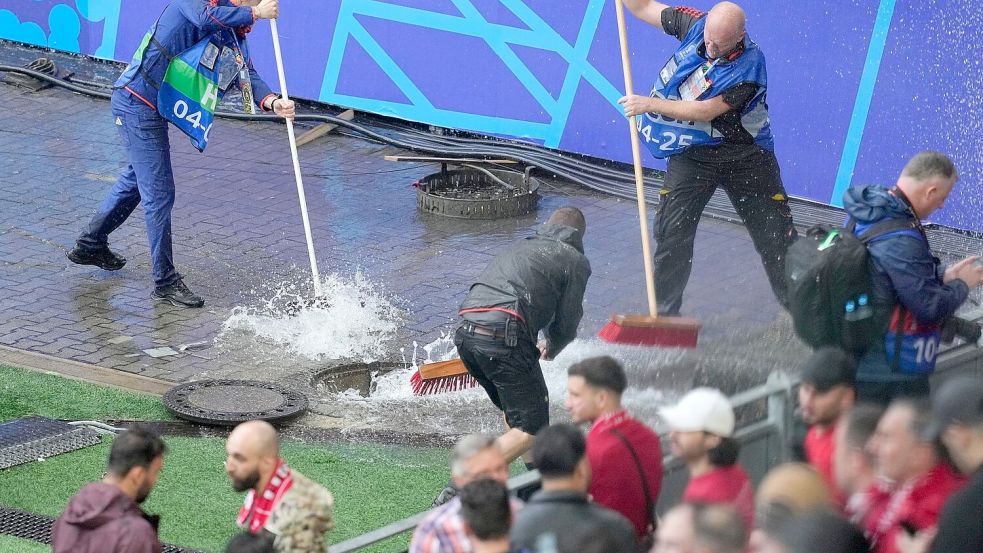 Kampf gegen die Wassermassen: Mitarbeiter sind vor dem Spiel Türkei gegen Georgien im Stadion im Einsatz. Foto: Andreea Alexandru/AP