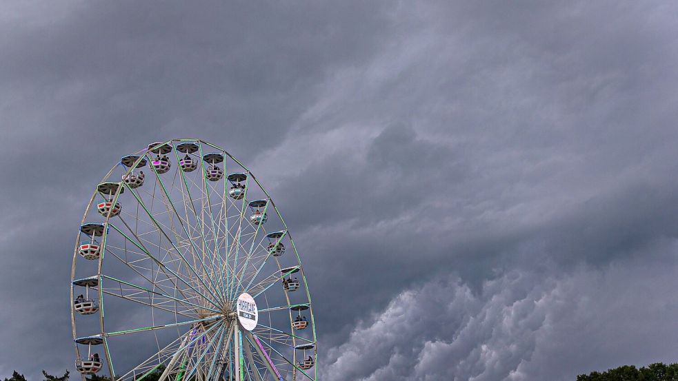 Dunkle Regenwolken ziehen über ein Riesenrad auf dem Gelände des Hurricane-Festivals in Scheeßel hinweg. Foto: Moritz Frankenberg/dpa