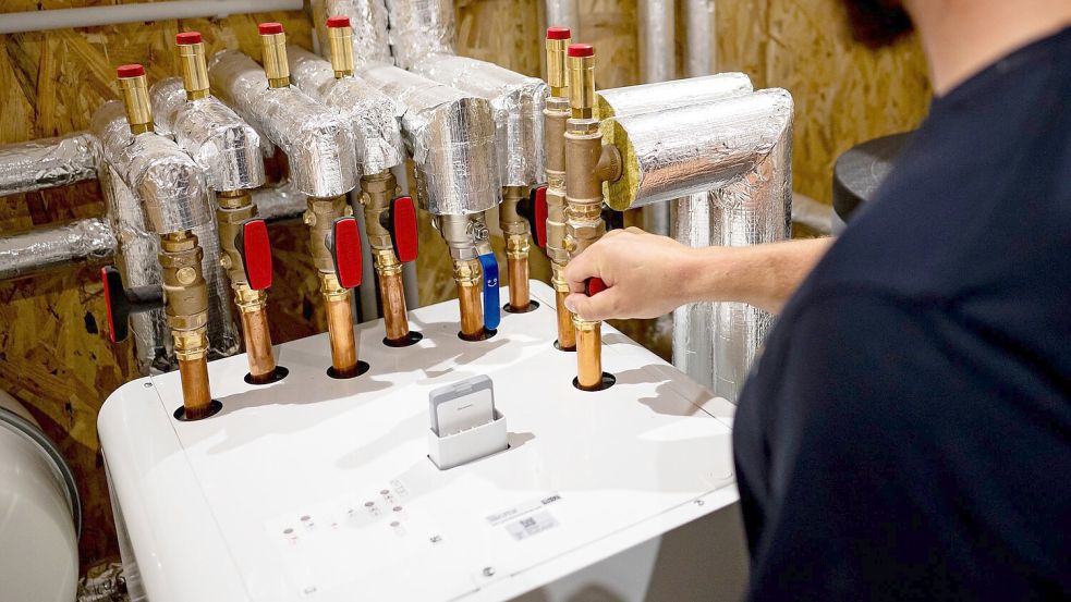 Ein Handwerker arbeitet an einer Wärmepumpe. Bei den Geräten ist die Nachfrage eingebrochen. Foto: Fabian Sommer/dpa