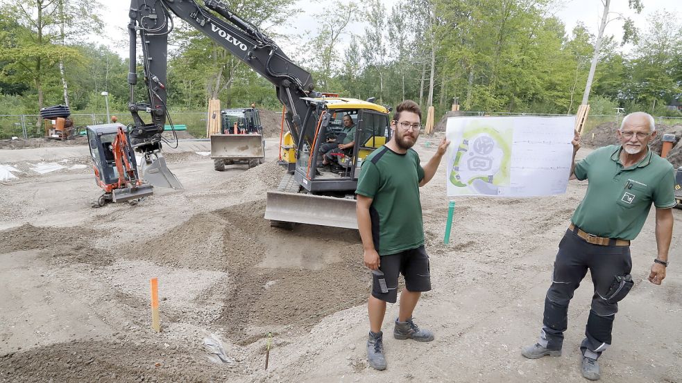 Mit den vorbereitenden Arbeiten für den Bau des Skateparks beim Sportpark Barßel ist begonnen worden. Martin Nintemann (links) und sein Vater Marten von der Gartenbaufirma Marsmann, die daran mitwirkt, halten auf der Baustelle eine Planzeichnung in die Höhe. Foto: Passmann