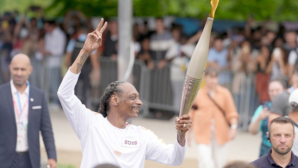 Für manche überraschend: Der US-amerikanische Rapper Snoop Dogg trägt beim Fackellauf das Olympische Feuer. Foto: dpa/Marcus Brandt