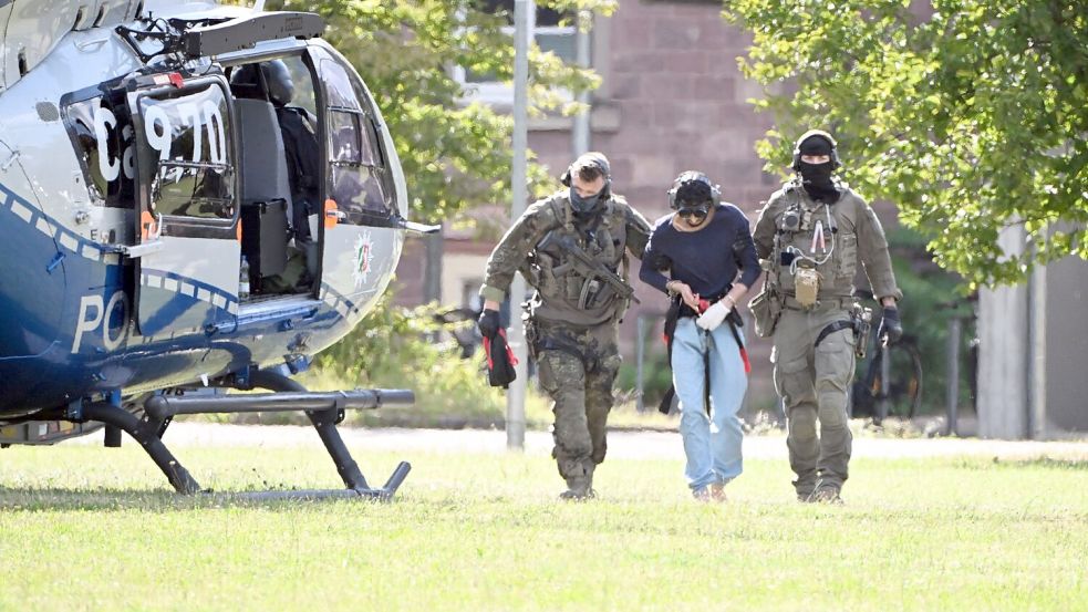 Der Tatverdächtliche wurde in Karlsruhe von bewaffneten Polizisten in Spezialausrüstung vom Helikopter zu einer Wagenkolonne gebracht. Foto: Uli Deck/dpa