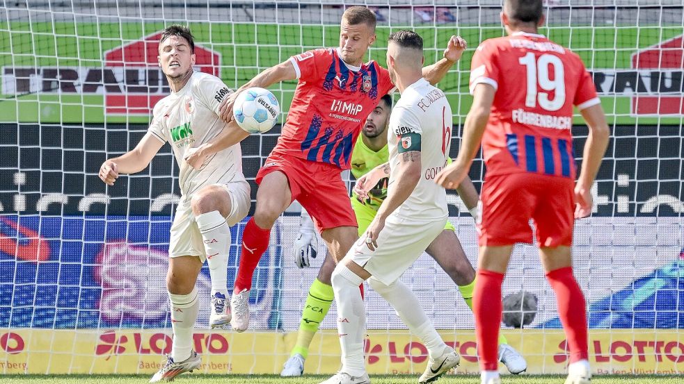 In dieser Szene berührt Augsburgs Schlotterbeck den Ball mit dem linken Arm. Die Folge: Handelfmeter für Heidenheim. Foto: Harry Langer/dpa