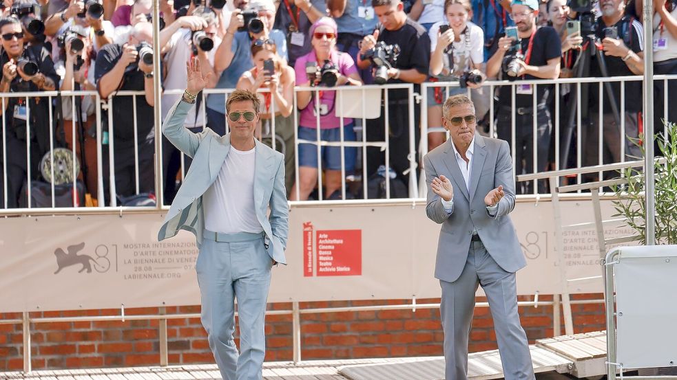 George Clooney und Brad Pitt werden in Venedig von begeisterten Fans empfangen. Foto: Vianney Le Caer/Invision/AP/dpa