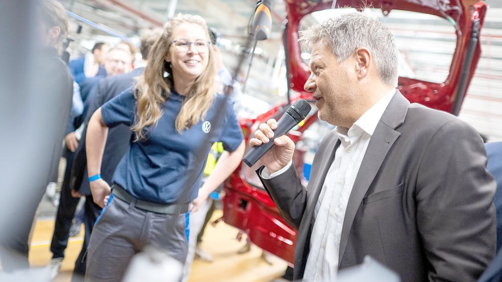 Da greift der Wirtschaftsminister auch selbst zum Mikrofon: Robert Habeck spricht im Emder VW-Werk mit einer Mitarbeiterin. Foto: Schuldt/DPA