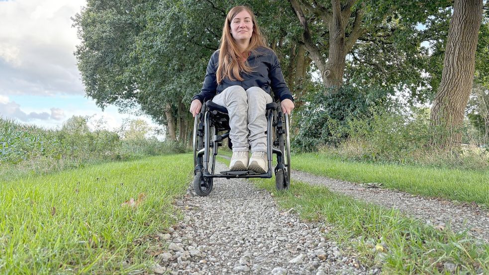 Die vielen dickeren Schottersteine auf dem Ostfriesland-Wanderweg bereiten Lara Brink, die auf einen Rollstuhl angewiesen ist, Probleme. Wenn dann noch in der Mitte des Weges das Gras aus dem Schotter wächst, wird es schwierig für die 25-Jährige, dort mit dem Rolli zu fahren. Foto: Ammermann