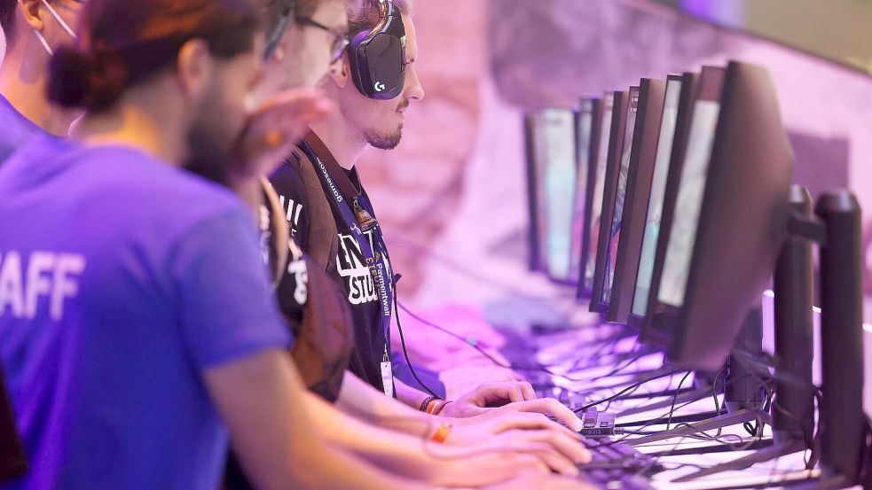 Messebesucher testen ein Computerspiel bei der Gamescom 2022. Foto: Oliver Berg/dpa