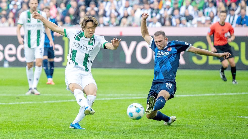 Der Mönchengladbacher Ko Itakura (l) trifft in dieser Szene zum 1:1, Heidenheims Jonas Föhrenbach grätscht zu spät dazwischen. Foto: David Inderlied/dpa