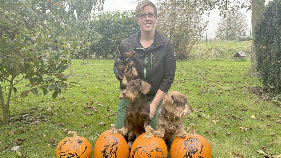 Dackelzüchterin Annika Behrendt aus Dorenborg mit ihren Dackeln „Distel“ (auf dem Arm), „Toti“ (links) und „Pid“ vor Kürbissen mit Dackelmotiven. Foto: Ammermann