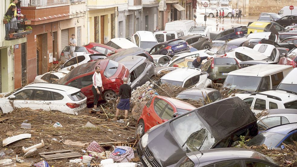 Nach den Überflutungen in und um Valencia stehen Anwohner zwischen Autos, die durch Wassermassen aufgestapelt wurden. Foto: AP/Alberto Saiz