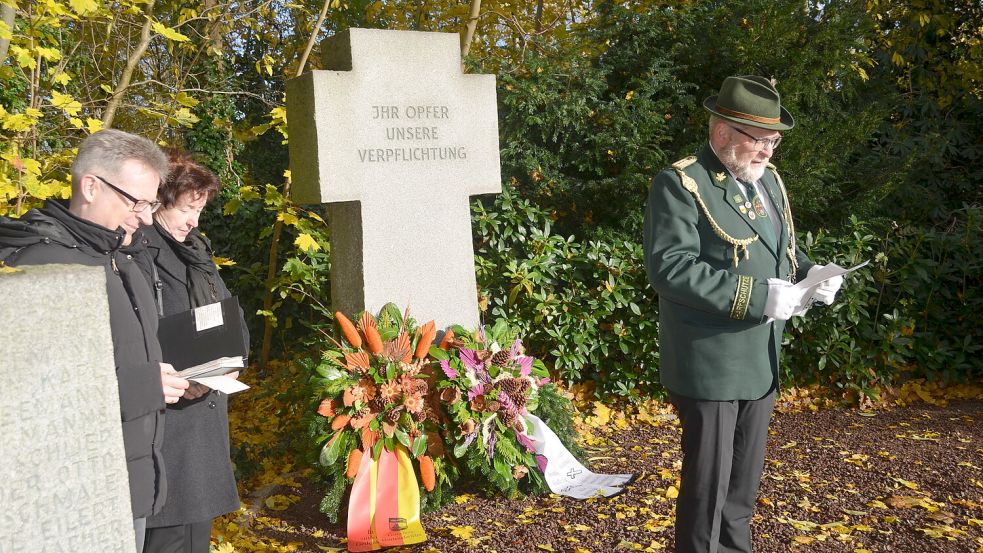 Werner Thomßen, Ehrenvorsitzender des Idafehntjer Schützenvereins "Eiche" hielt im Beisein von Pastor Florian Bortfeldt (links) und Lydia de Boer von der Gemeinde Ostrhauderfehn eine Ansprache am Denkmal für Kriegsopfer in Idafehn. In seiner Rede ermahnte Thomßen alle, nicht tatenlos zuzusehen angesichts von Krieg und Unrecht, sondern gemeinsam für eine Welt zu kämpfen, in der jeder Mensch in Frieden leben kann. Foto: Fertig