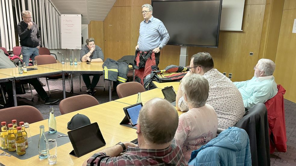 Westoverledingens Gemeindebrandmeister Frank Harms (Mitte, stehend) erläuterte den Mitgliedern des Feuerwehrausschusses die neue Einsatzkleidung. Auf dem Foto präsentiert er eine Einsatzhose. Foto: Ammermann