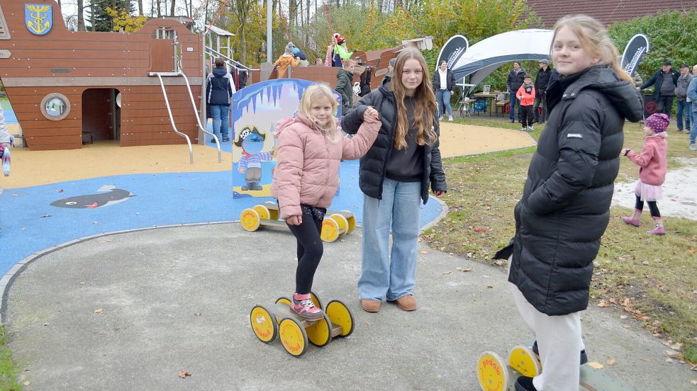 Auf Rollbrettern waren bei der Spielplatzeröffnung unterwegs (von links) Laura, Laura-Mia und Leevke. Dessen Herzstück ist das Piratenschiff mit dem Namen Fehntje, dessen Inneres komplett mit dem Rollstuhl befahrbar ist. Foto: Fertig