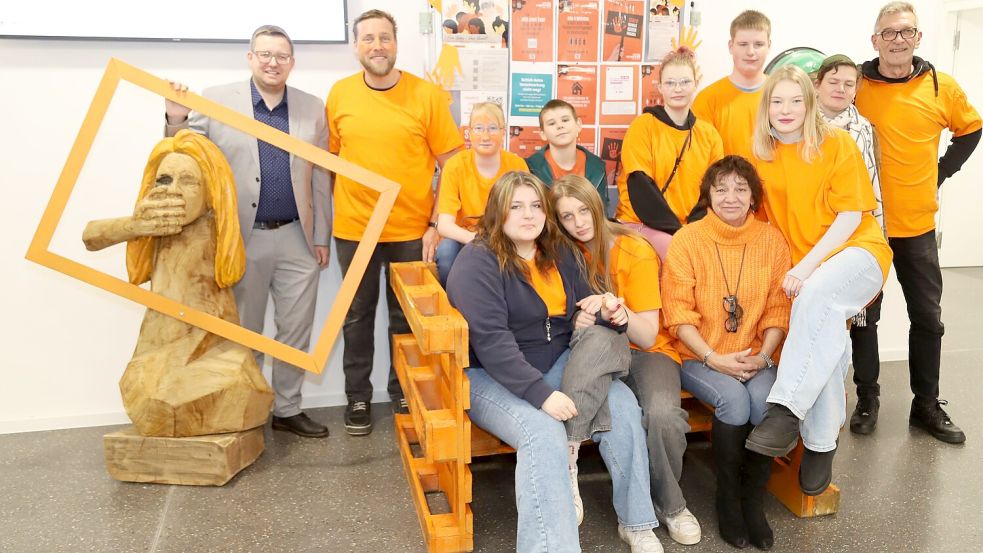 Im Atrium des Barßeler Rathauses machen die Schülerinnen und Schüler sowie die Lehrkräfte der Soeste-Schule am „Orange Day“ mit einer Sitzbank und Frauenfigur auf die Gewalt gegen Frauen in den nächsten 16 Tagen aufmerksam. Foto: Passmann