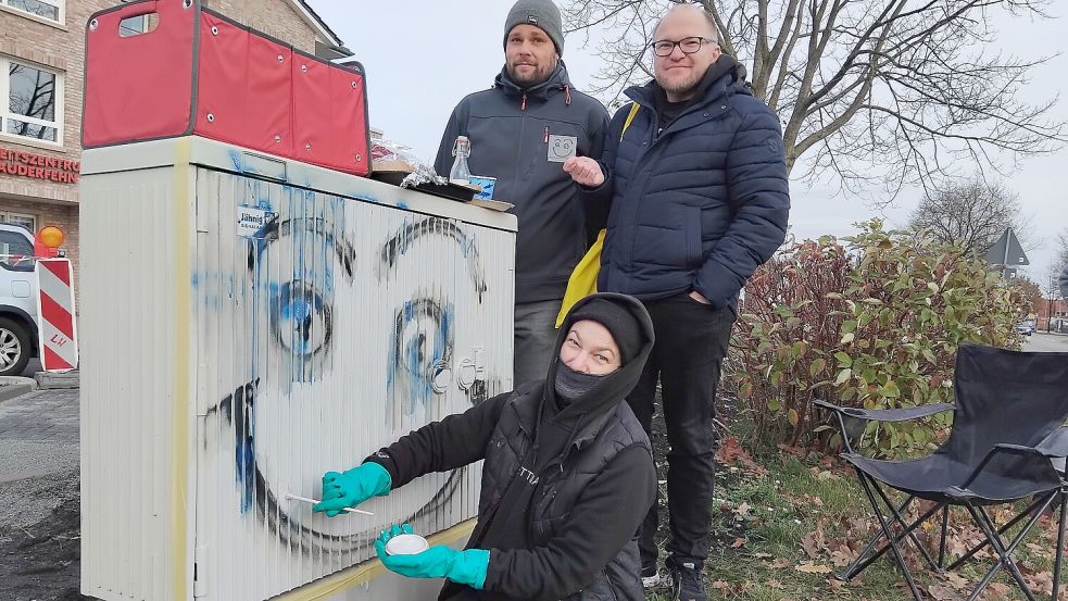 Marcel Wolter (links), Mathias Uslar und Künstlerin „Dolly Dollart“ sind treue „Klotzi“-Fans. Sie haben den Schaltkasten jetzt wieder schick gemacht. Fotos: Scherzer