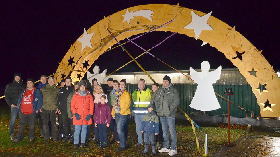 Ein Großteil der Nachbarschaft, die sich am Bau des weihnachtlichen Schwibbogens an der 2. Südwieke in Rhauderfehn beteiligt hat, hat sich unmittelbar vor dessen Vollendung vor dem Gemeinschaftswerk aufgestellt. Foto: Fertig