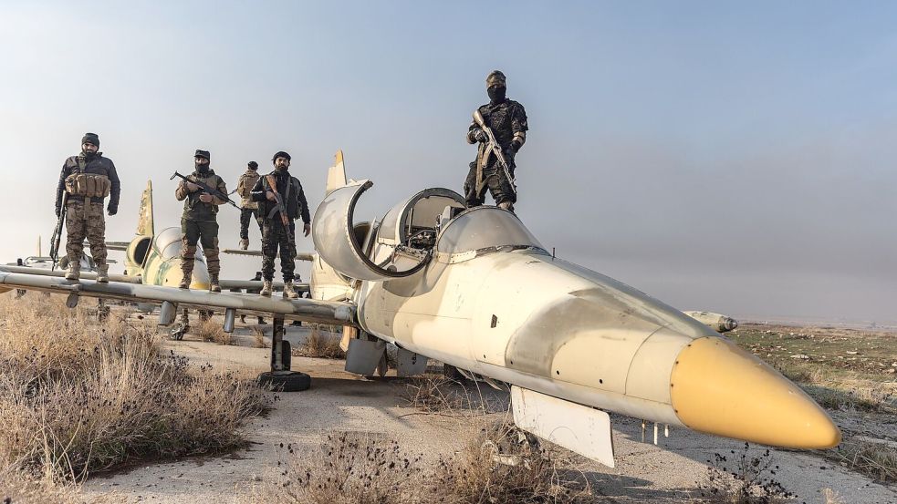 Mitglieder der bewaffneten Opposition zeigen sich auf einem Kampfjet. Das Foto von Anas Alkharboutli entstand, nachdem die Rebellen die Kontrolle über den Militärflughafen Nayrab in der Stadt Aleppo übernommen haben. Foto: Anas Alkharboutli/dpa