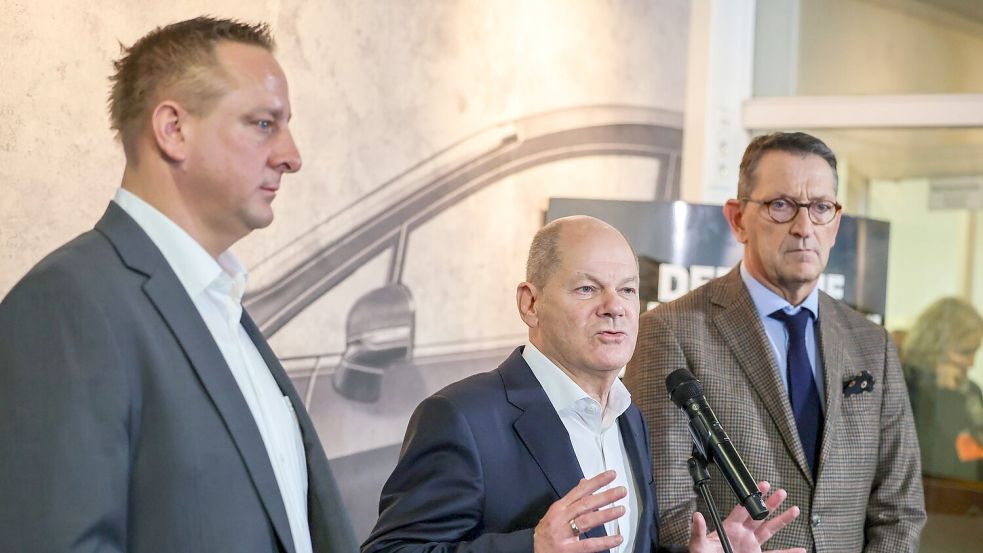 Betriebsratschef Benjamin Gruschka (l) neben Bundeskanzler Olaf Scholz (SPD) und Marcus Wassenberg (r), Geschäftsführer der Ford-Werke. Foto: Christoph Reichwein/dpa