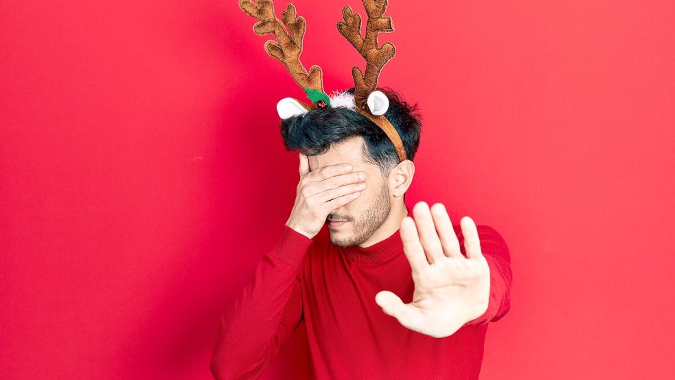 Young hispanic man wearing cute christmas reindeer horns covering eyes with hands and doing stop ges Foto: imago/depositphotos