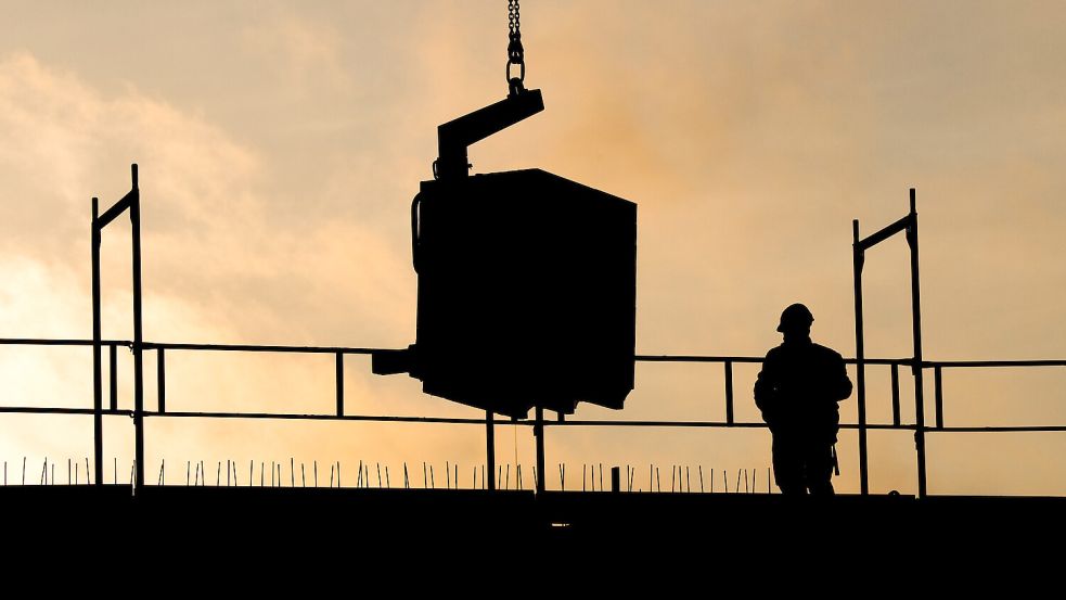 Bauarbeiter bauen bei Sonnenaufgang an einem Wohnhaus. Foto: Julian Stratenschulte/dpa