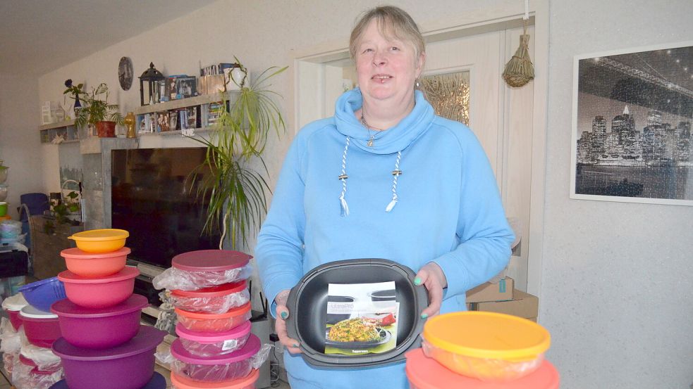 Die Rhauderfehner Tupperberaterin Birgit Gerdes inmitten ihrer im Wohnzimmer aufgebauten Ware. In der Hand hat sie den Bräter „Ultra“. Den hat sie sich nach der Insolvenz von Tupperware Deutschland auch für den privaten Gebrauch noch rasch gesichert. Foto: Fertig