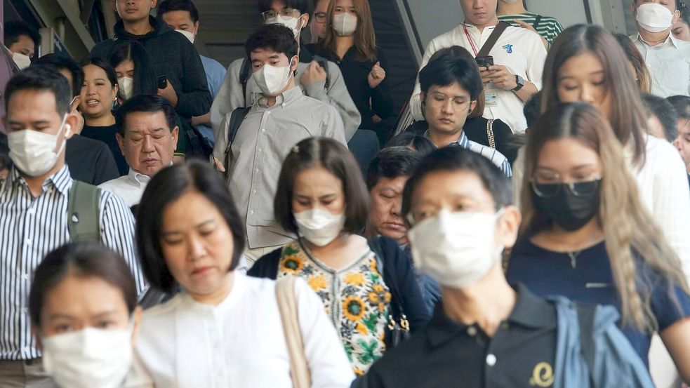 Pendler tragen Gesichtsmasken, um sich vor der Luftverschmutzung zu schützen. Foto: Sakchai Lalit/AP/dpa