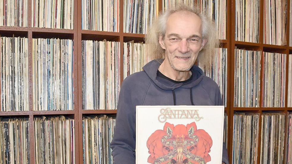 Uwe Müller mit einem Plattencover von Carlos Santana. Die Platte ist eine von rund 7000 LPs, die Müller in den frühen Jahren seines Jobs brauchte. Foto: Götting