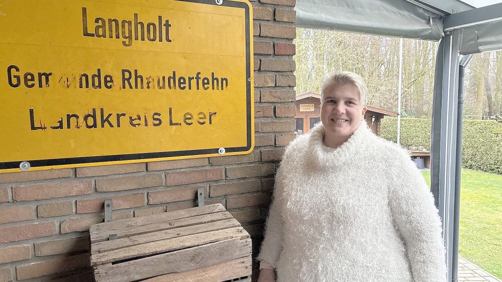 Andrea Meiners steht in Langholt auf ihrer Terrasse neben dem Ortsschild. Foto: Kruse