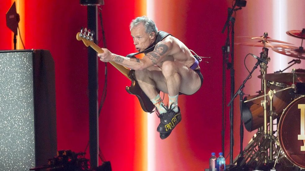 Flea von den Red Hot Chili Peppers macht Luftsprünge. Foto: Chris Pizzello/Invision/AP/dpa