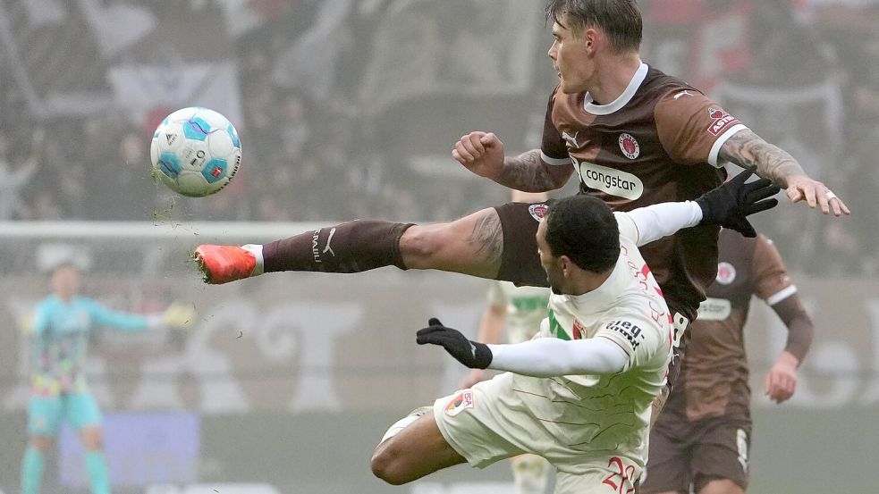 St. Paulis Eric Smith (r) und Augsburgs Alexis Claude-Maurice kämpfen um den Ball. Foto: Marcus Brandt/dpa