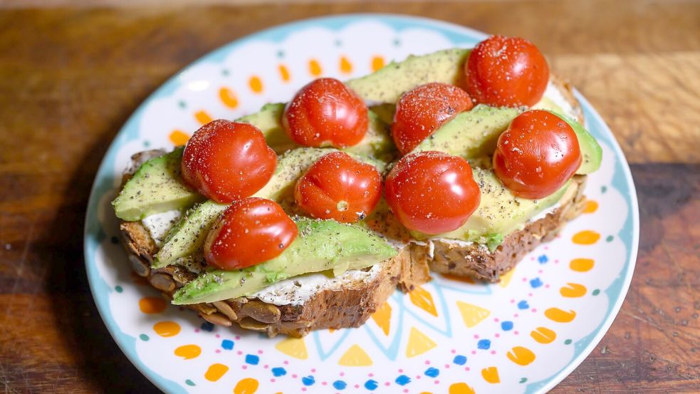 Eine Scheibe Kürbiskernbrot mit Avocado und Tomaten. Viele jüngere Leute in Deutschland sehen sich eher als Avocadobrot- denn Wurstbrot-Typ. (Symbolbild) Foto: Robert Michael/dpa