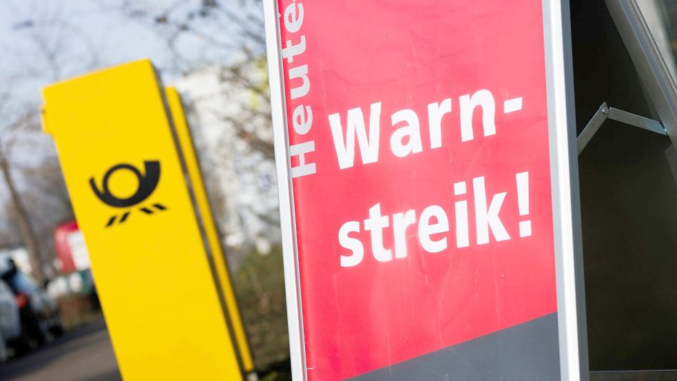 Ein Warnstreik-Schild bei einem Post-Standort, daneben ein Briefkasten - im Ringen um einen Tarifabschluss haben Tausende Postler erneut die Arbeit niedergelegt. Foto: Philipp von Ditfurth/dpa