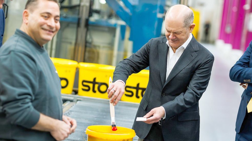 Kanzler Scholz macht beim Baustoffhersteller Sto eine Farbenprobe. Foto: Philipp von Ditfurth/dpa