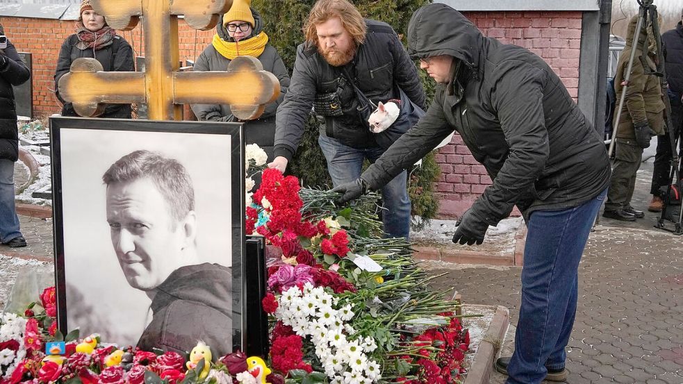 Menschen legen ein Jahr nach dem Tod des russischen Oppositionsführers Alexej Nawalny auf dem Borisowskoje-Friedhof in Moskau Blumen an seinem Grab nieder. Foto: Uncredited/AP/dpa