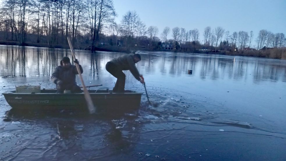 Maik Völter und Frank Poelker schlagen per Spaten einen Weg durchs Eis, um das kuriose Fundstück zu bergen. Foto: Scherzer