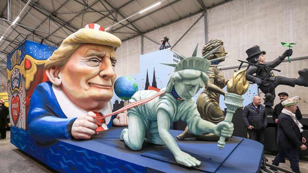 Einer der Wagen im Kölner Rosenmontagszug zeigt US-Präsident Donald Trump, der die Freiheitsstatue und die Justitia am Laufband führt. Foto: Oliver Berg/dpa