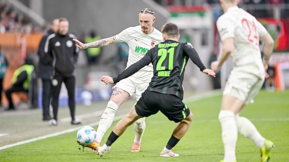 Augsburgs Marius Wolf spielt den Ball an Joakim Maehle von Wolfsburg vorbei. Foto: Harry Langer/dpa